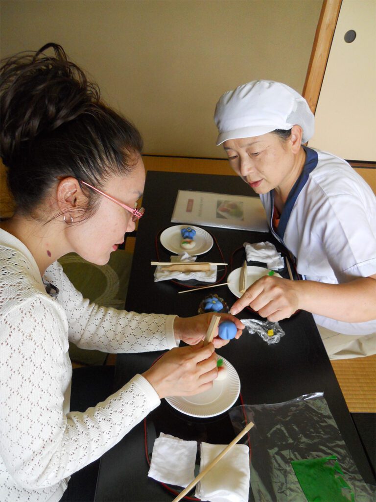 星野村の「茶の文化館」で地元の職人と一緒に和菓子を作ろう 2 A participant shaping wagashi under the guidance of Ms. Ishibashi, who points out delicate details during a hands-on sweets-making workshop at Hoshino Tea Museum