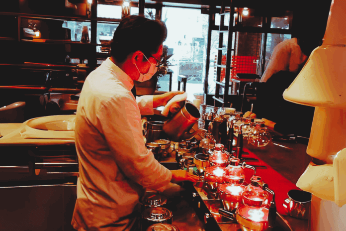Barista brewing siphon coffee in a science experiment style at Noda Coffee Shop, Fukuoka.